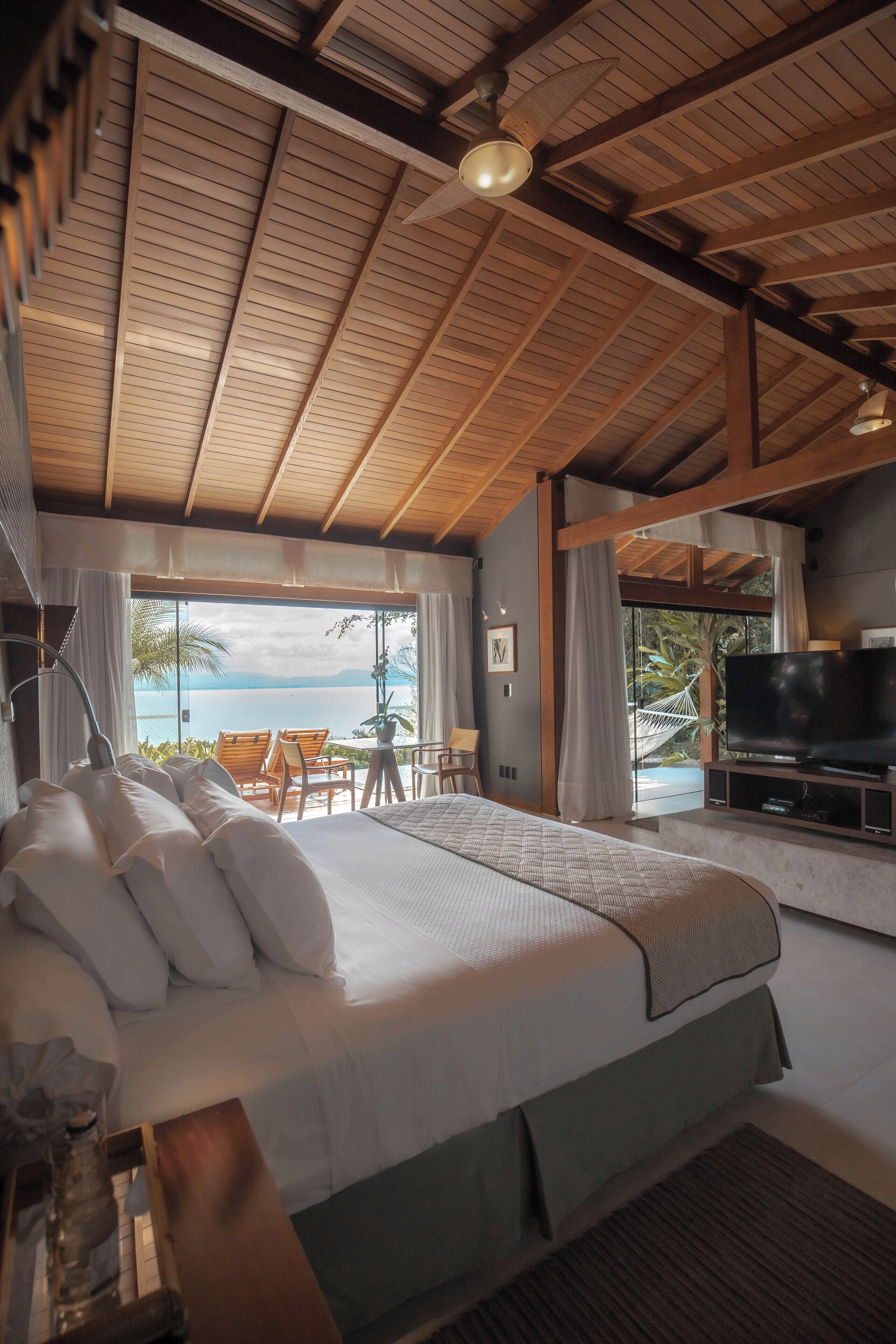 Un dormitorio con una cama grande, televisión y vista al mar.