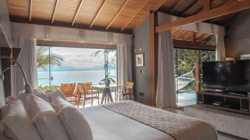 Un dormitorio con una cama grande, televisión y vista al mar.
