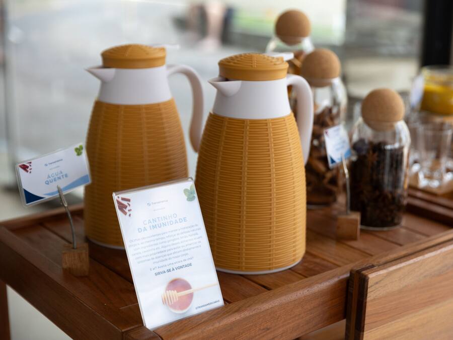 Een houten presentatietafel met twee gele schenkkan en een bordje met de tekst Cantinho da Imunidade.