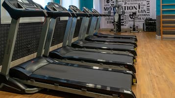 Varias caminadoras en un gimnasio, con un letrero motivacional al fondo.
