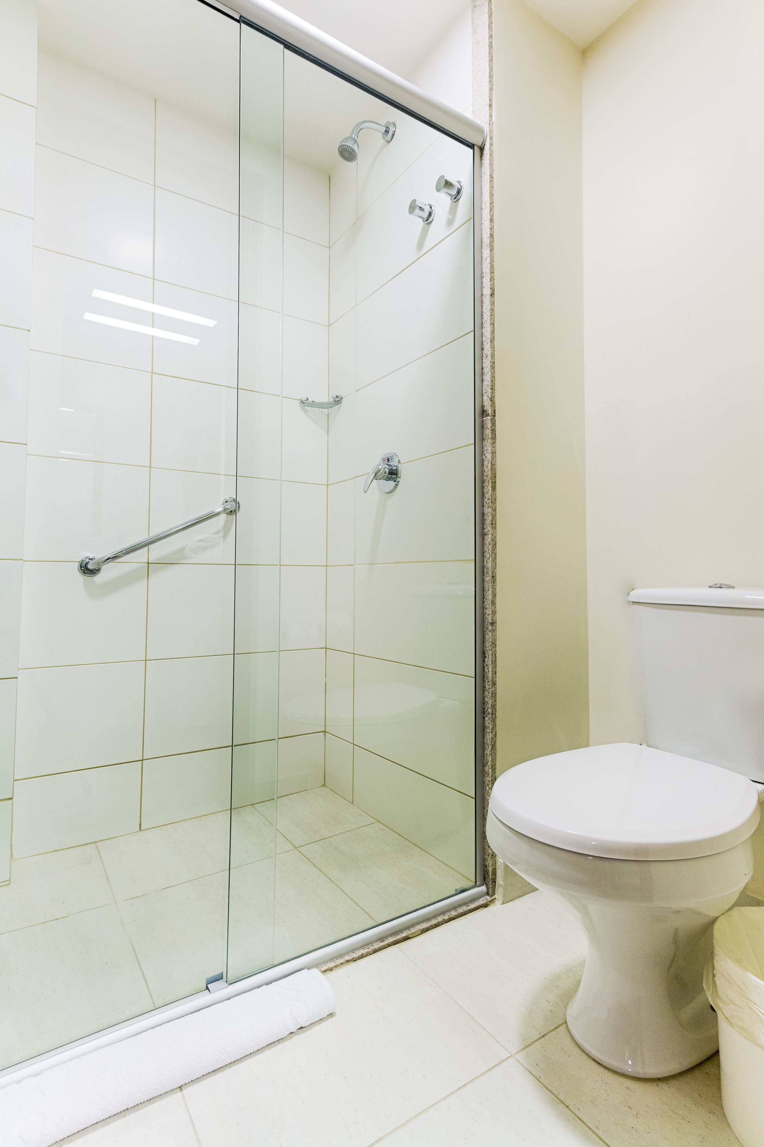 A bathroom with a glass-enclosed shower, a white toilet, and a visible shower control panel.