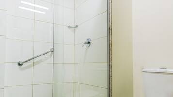 Un baño con ducha acristalada, inodoro blanco y panel de control de la ducha a la vista.