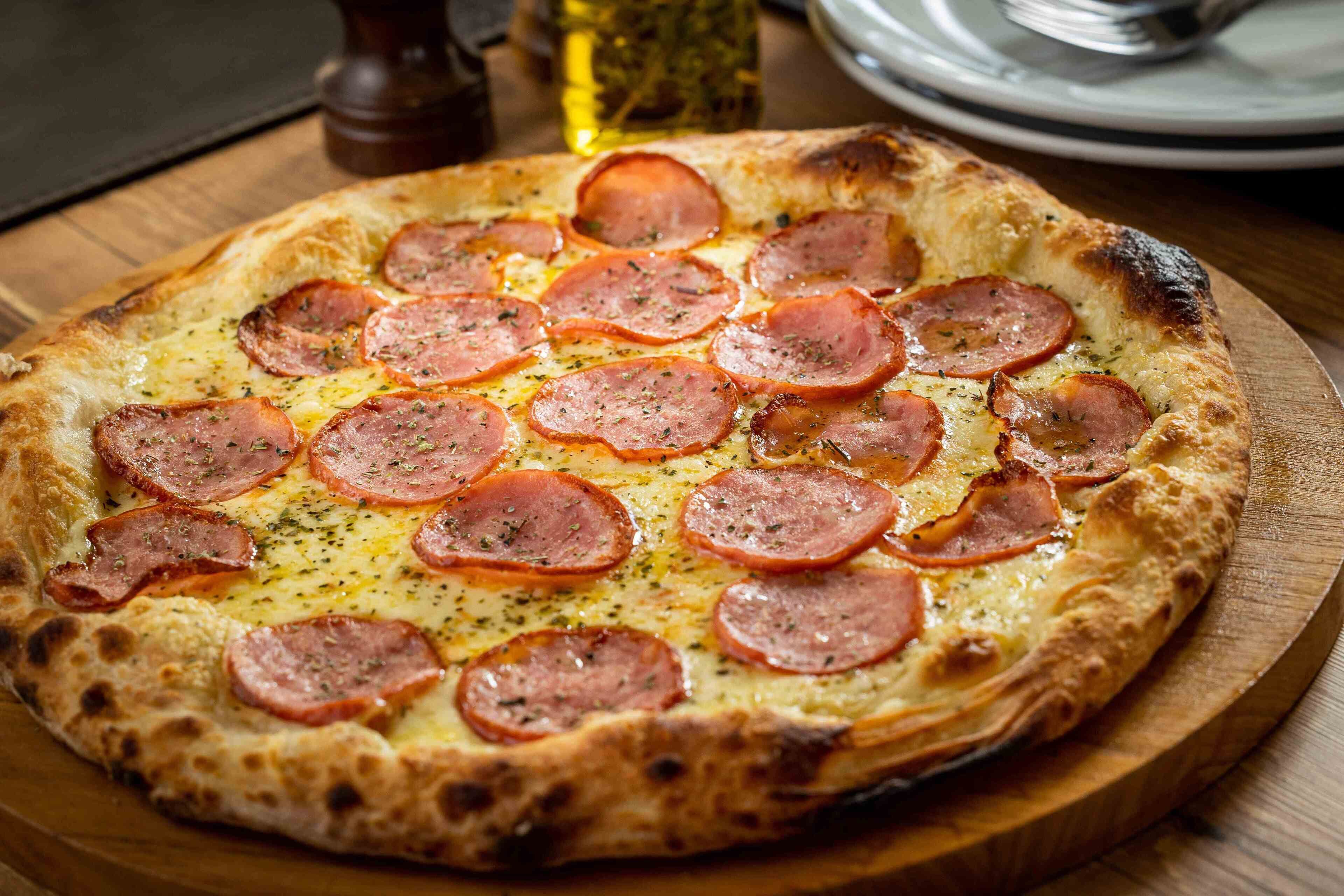 A pizza with pepperoni slices on a wooden board.