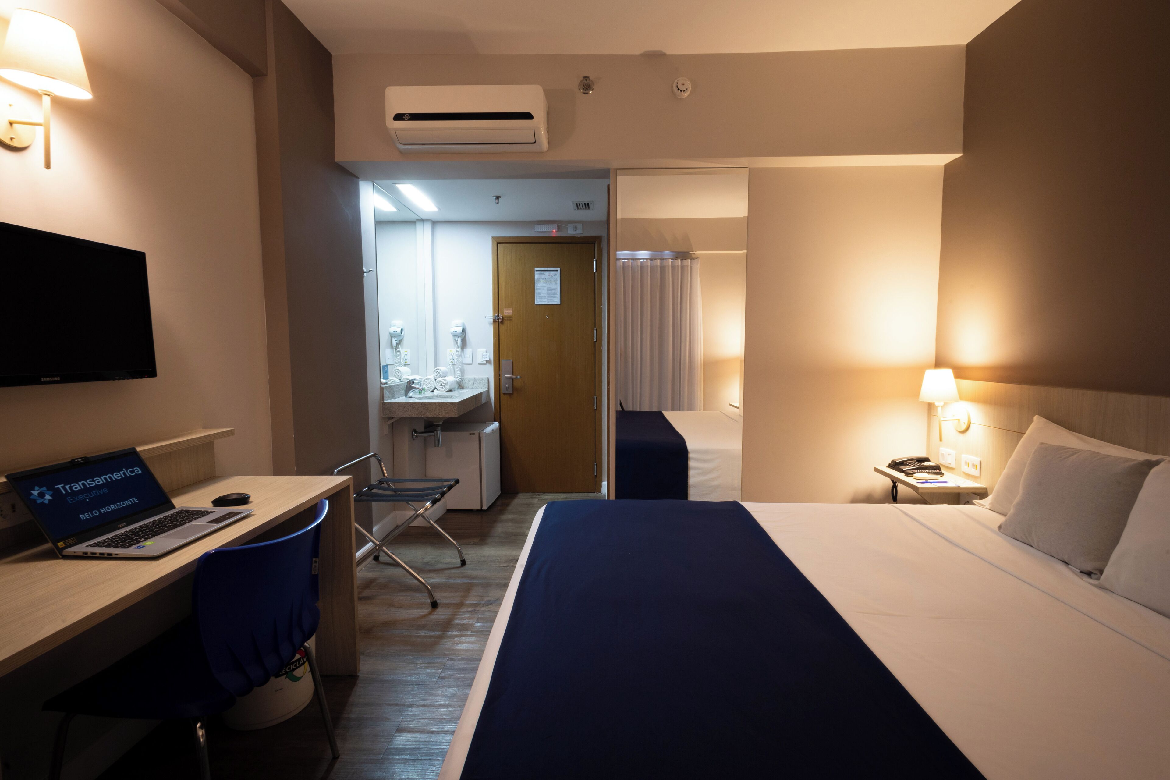 Una habitación de hotel con cama, escritorio, silla y televisor.
