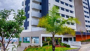 Un edificio moderno de varios pisos con balcones, un jardín ajardinado y vistas a la ciudad.