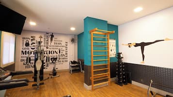 Un gimnasio con equipamiento de ejercicio, piso de madera y decoración de pared motivacional.