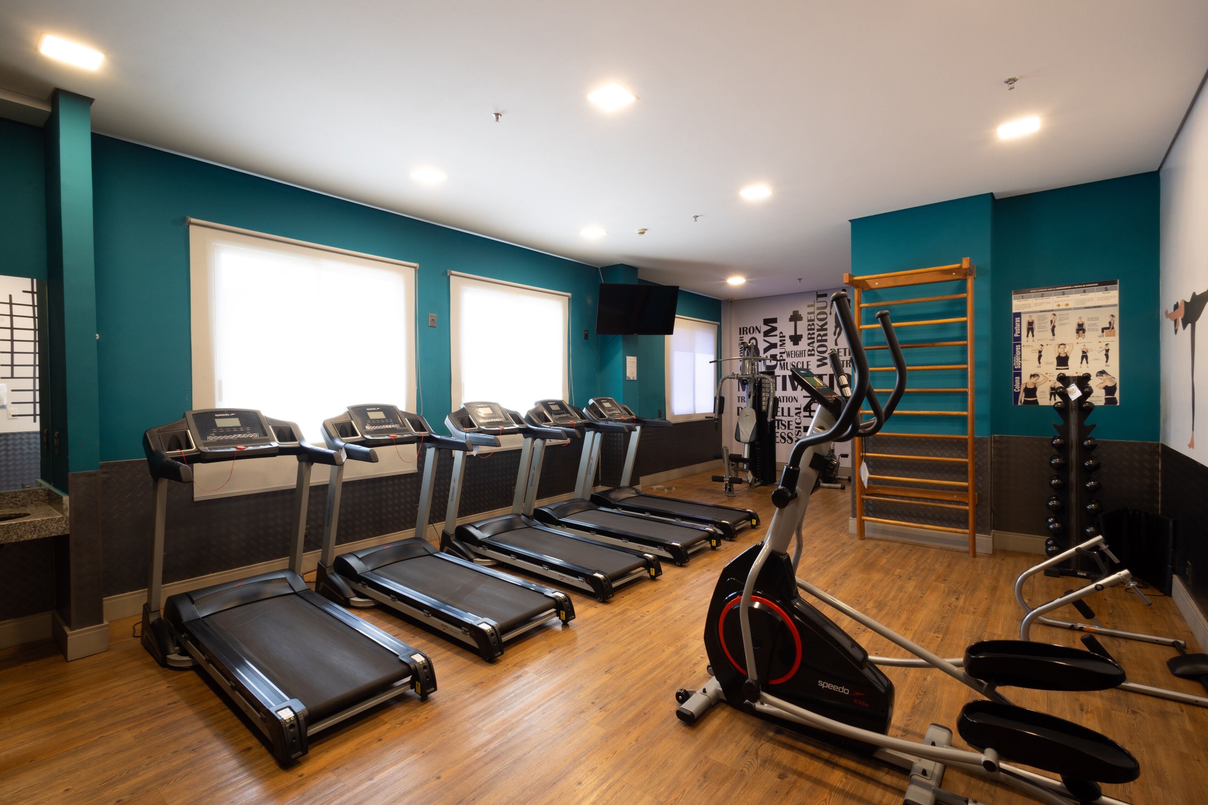 Un gimnasio con cintas de correr, elíptica y barra de dominadas.