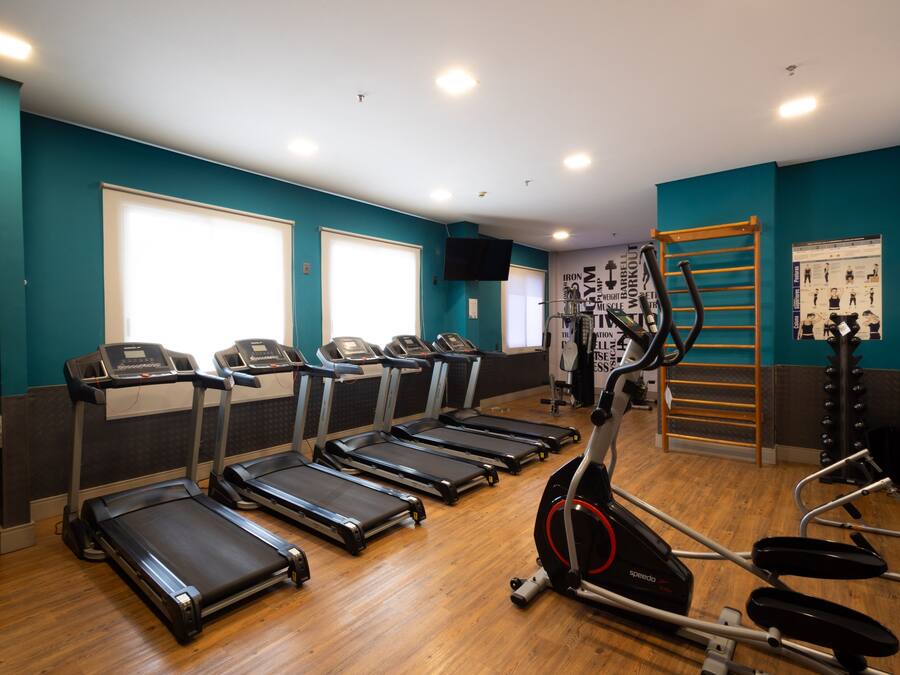 Un gimnasio con cintas de correr, elíptica y barra de dominadas.