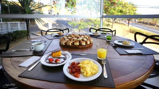 Una mesa de desayuno con platos de comida, una fruta, un vaso de zumo de naranja y un pastel.