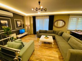 A modern living room with a sofa set, a coffee table, a TV, and a chandelier.