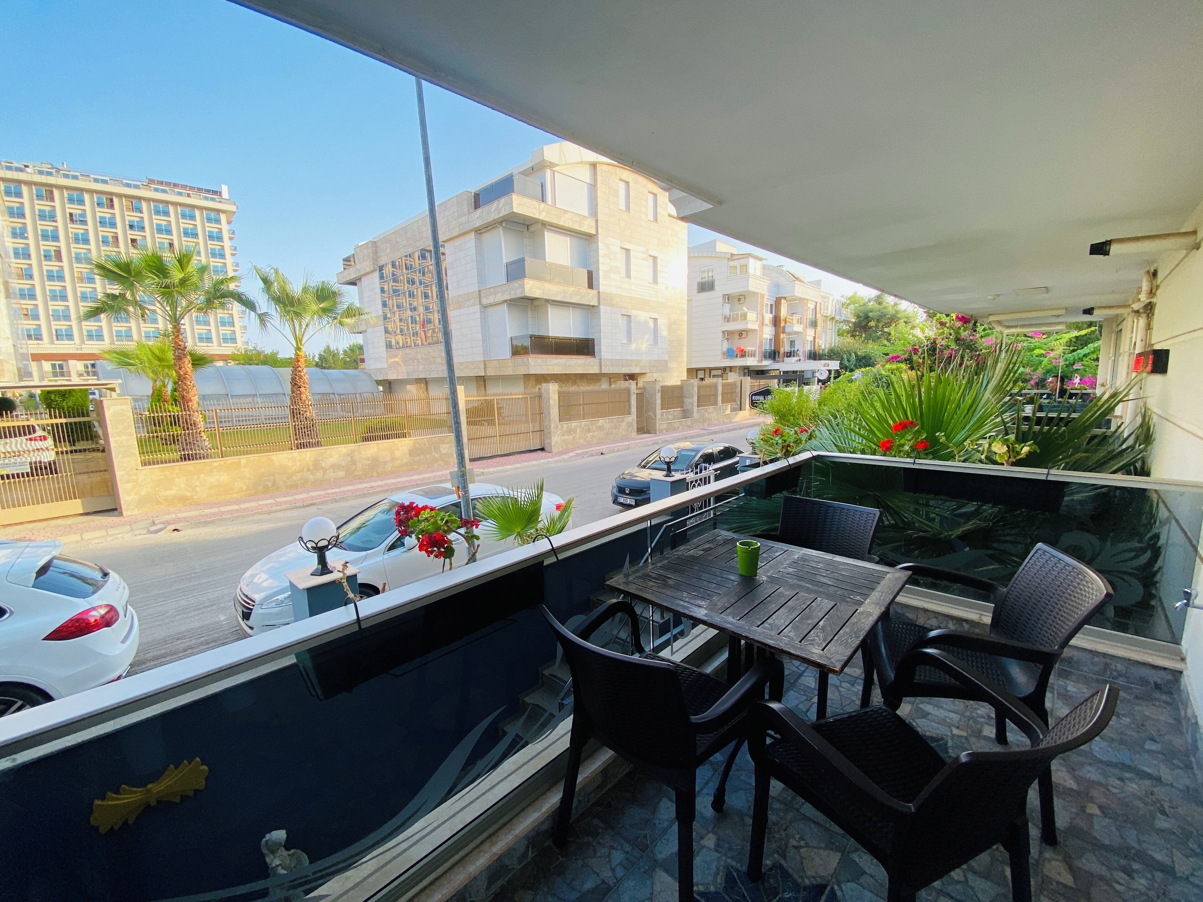 Ein Balkon mit Tisch und Stühlen, mit Blick auf eine Straße mit Autos und Gebäuden.