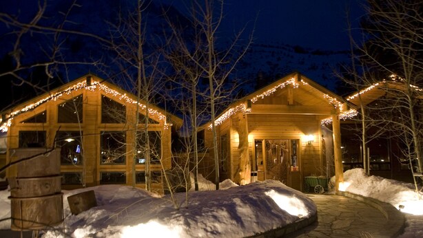 A wooden cabin with a covered porch and string lights, surrounded by snow. - Double Eagle Resort & Spa (June Lake)