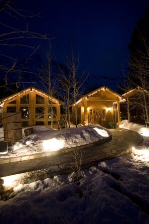 A wooden cabin with a covered porch and string lights, surrounded by snow. - Double Eagle Resort & Spa (June Lake)