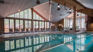 An indoor swimming pool with clear views of the surrounding forest, large windows, and a seating area with chairs. - Double Eagle Resort & Spa (June Lake)