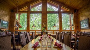 A wooden dining room with a large table set for six, surrounded by wicker chairs. - Double Eagle Resort & Spa (June Lake)