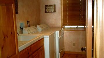 A laundry room with a washer and dryer, wooden cabinets, and a warning sign on the wall.