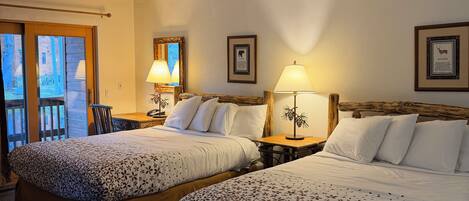A hotel room with two beds, a ceiling fan, and a view of the outside.