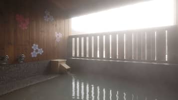 Un bain thermal en plein air, avec des murs et une rambarde en bois, ainsi qu’un banc.