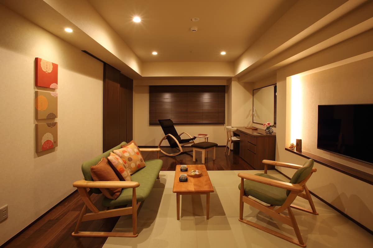 A compact living space with a sofa, two rocking chairs, a small table, and a TV.