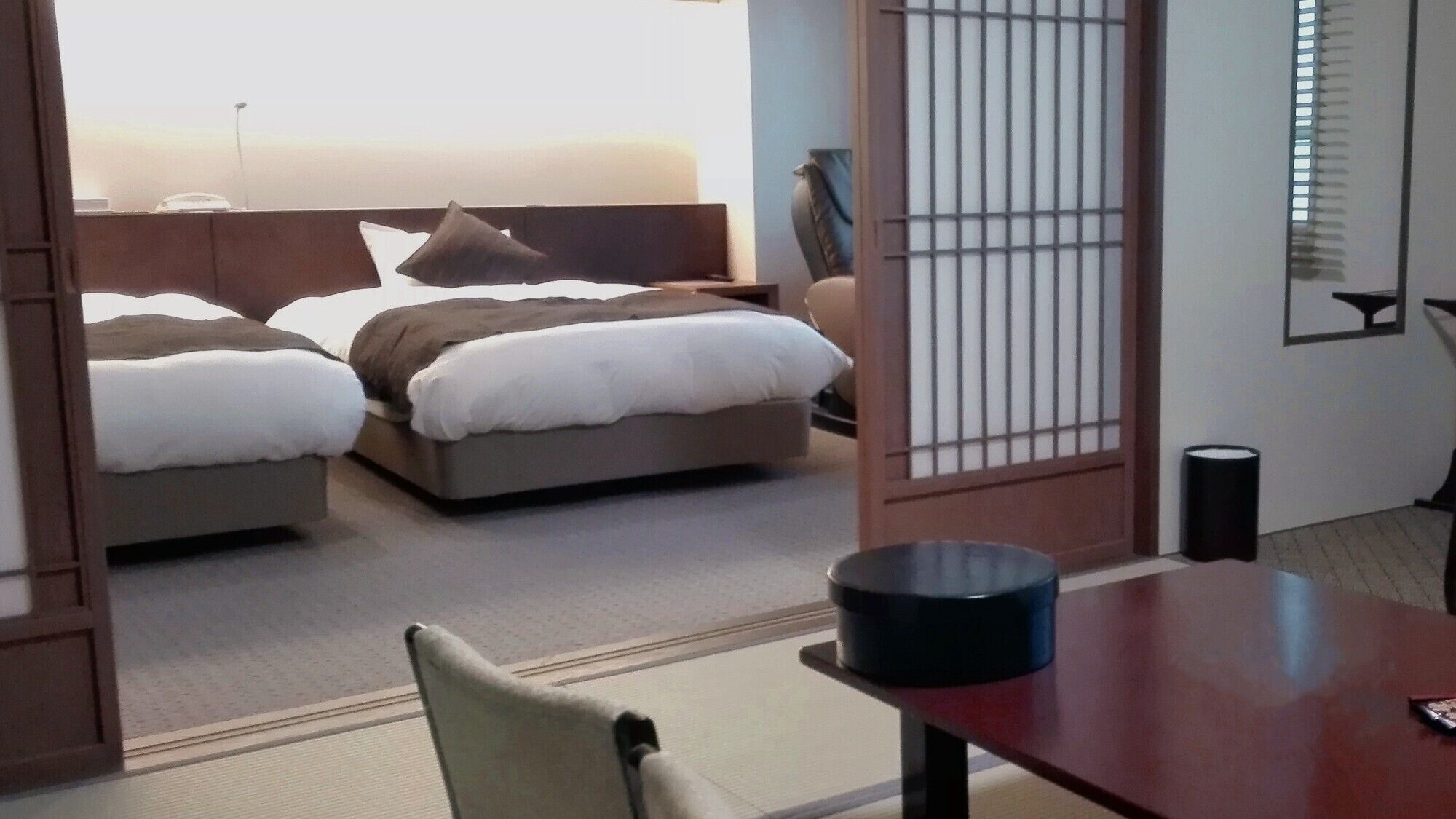 Habitación de hotel con dos camas, un escritorio de madera, una silla y vista al mar.