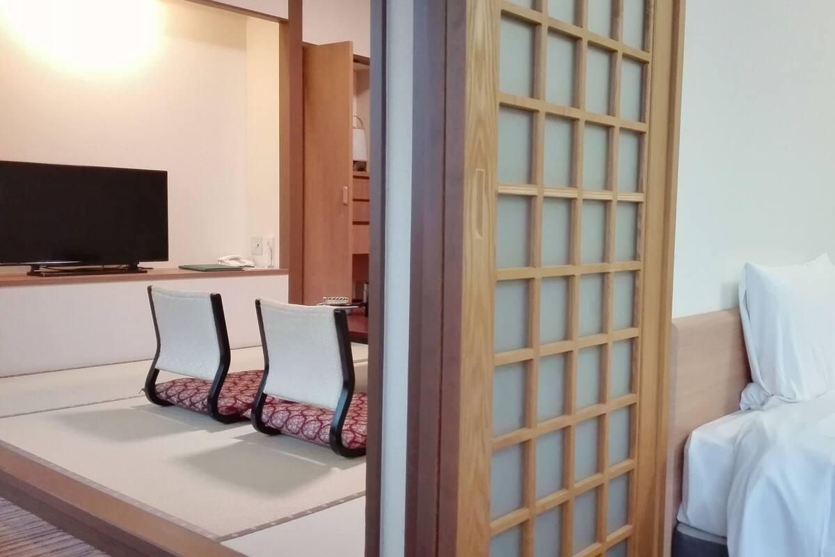A hotel room with a bed, a TV, a desk, and a chair.