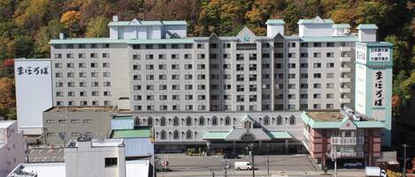 A large, multi-story building with a central entrance and a parking lot in front.