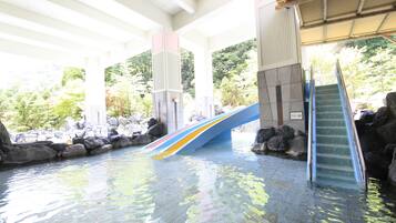 Relax by the tranquil water feature surrounded by lush greenery and a colorful slide.