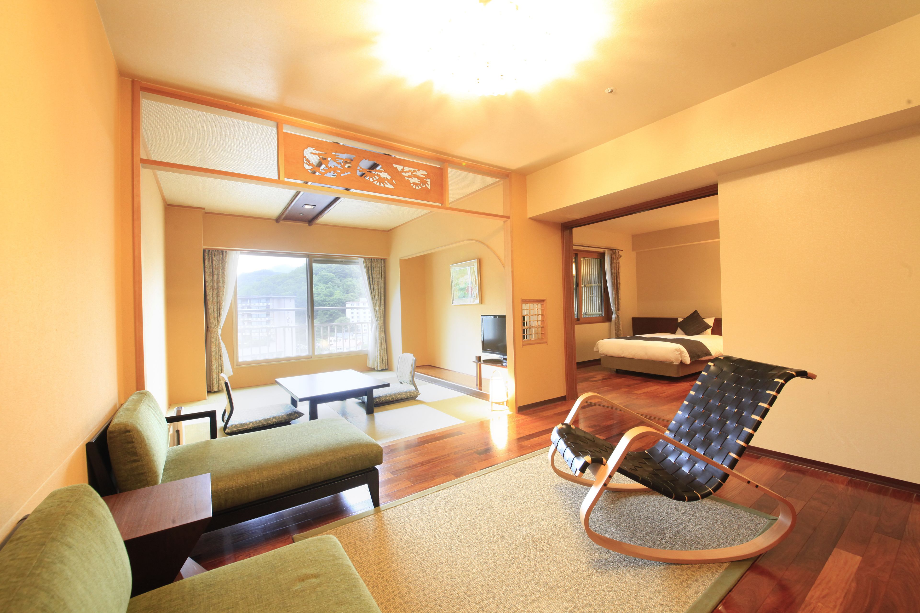 A room with a sofa, a chair, a television, and a bed.