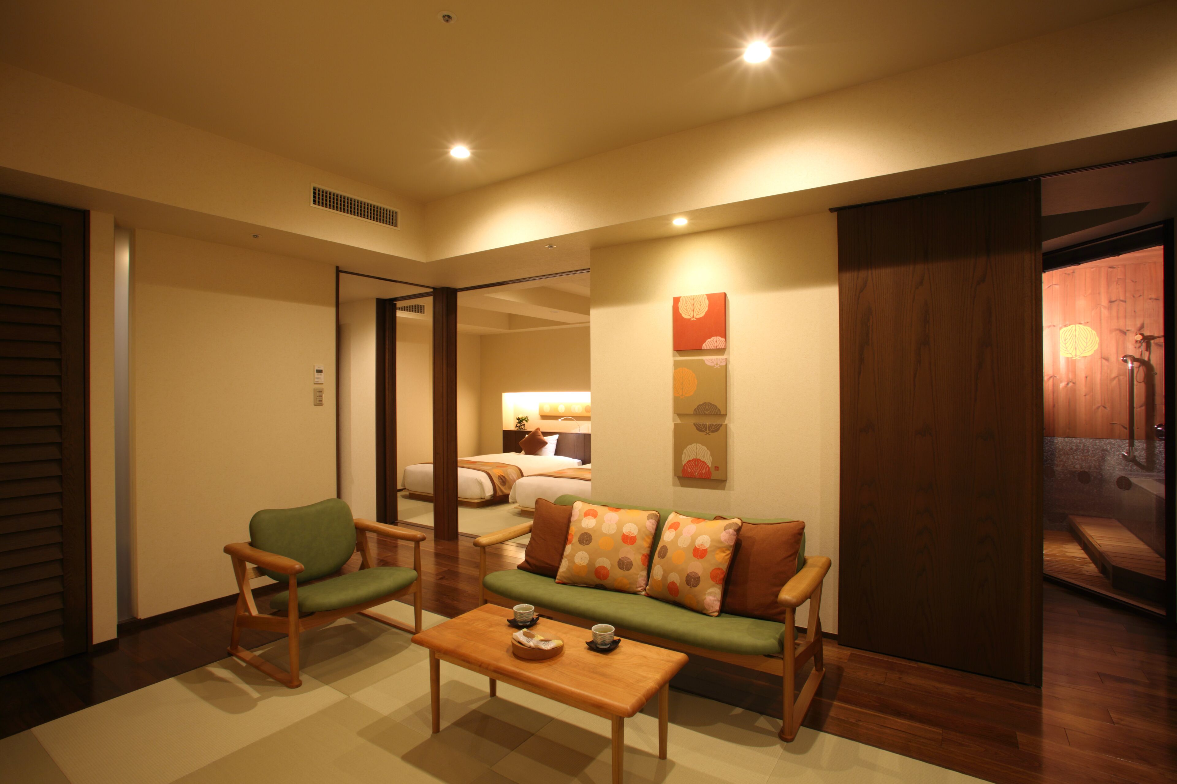 A modern living room with a sofa, two armchairs, and a coffee table. There is a sliding door leading to a bathroom.