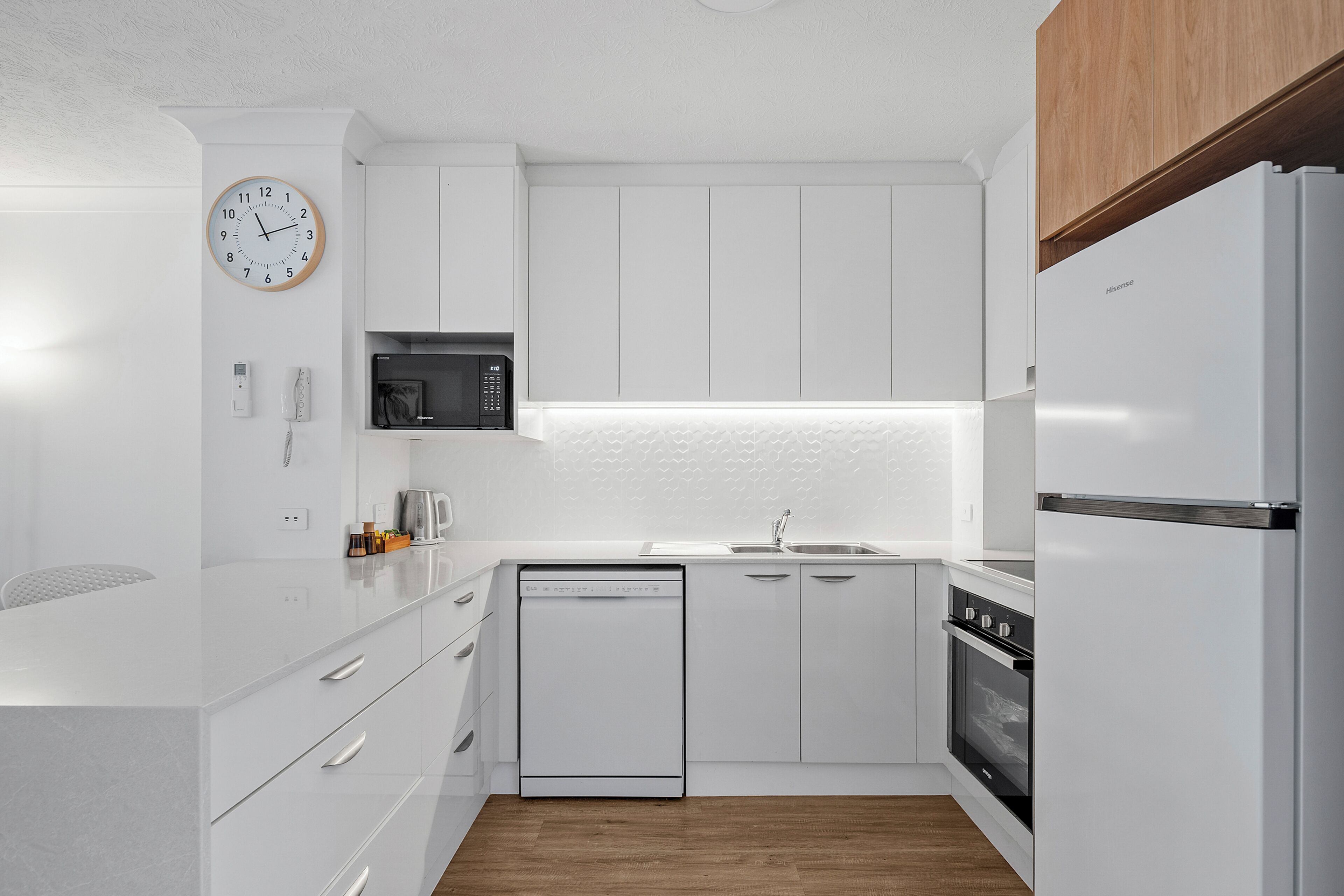 A modern kitchen with white cabinetry, a built-in microwave, a dishwasher, and a refrigerator.