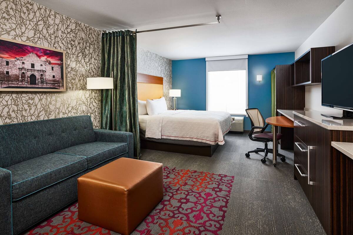 Ein Hotelzimmer mit Bett, Sofa, Schreibtisch und Fernseher.