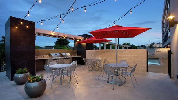 An outdoor patio with metal chairs, a barbecue grill, and string lights. - Home2 Suites by Hilton San Antonio Airport, TX (San Antonio)