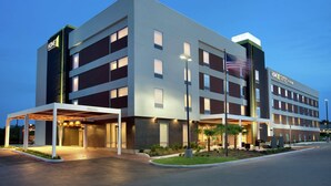 A modern hotel with a covered entrance, multiple floors, and a well-lit facade. - Home2 Suites by Hilton San Antonio Airport, TX (San Antonio)