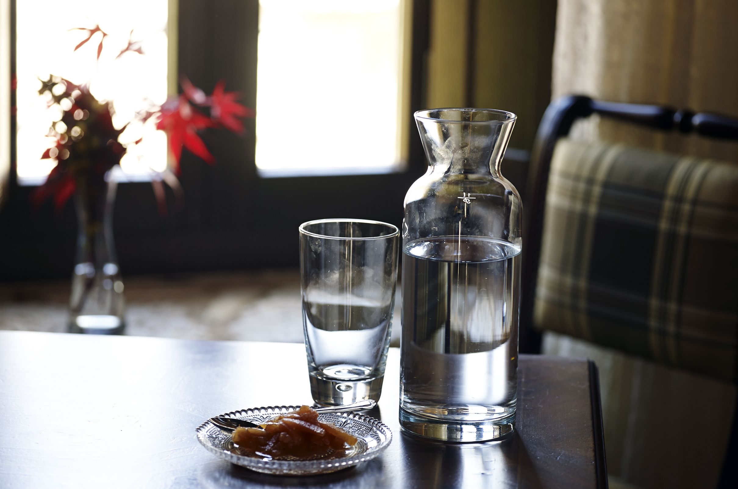 A table with a glass pitcher, a glass, and a plate with food.