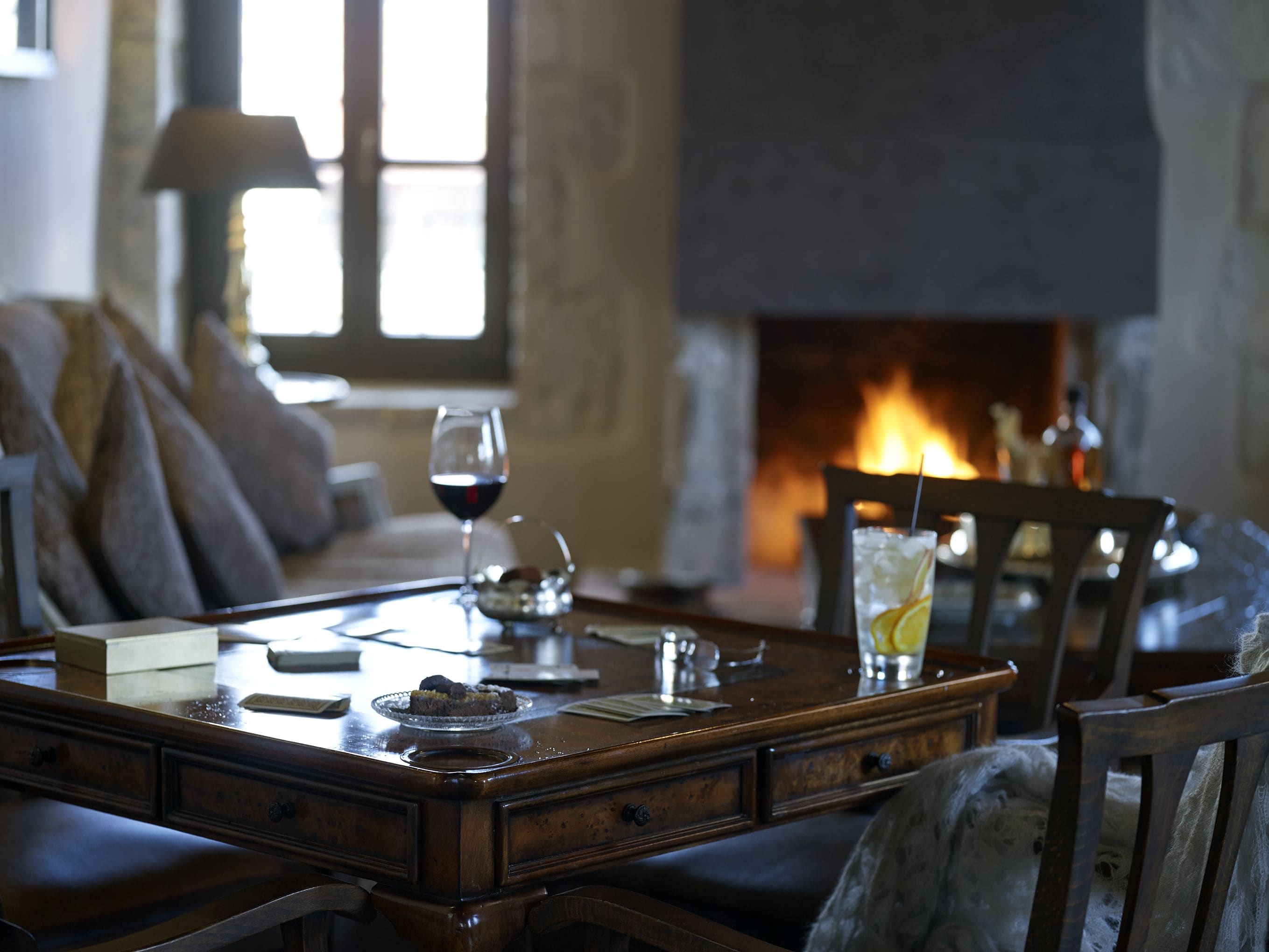 A cozy dining area with a fireplace, a table set for two, and a sofa in the background.