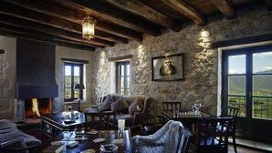 A rustic interior with stone walls, a fireplace, a sofa, and a dining table with chairs. - Villa Vager (Tripoli)