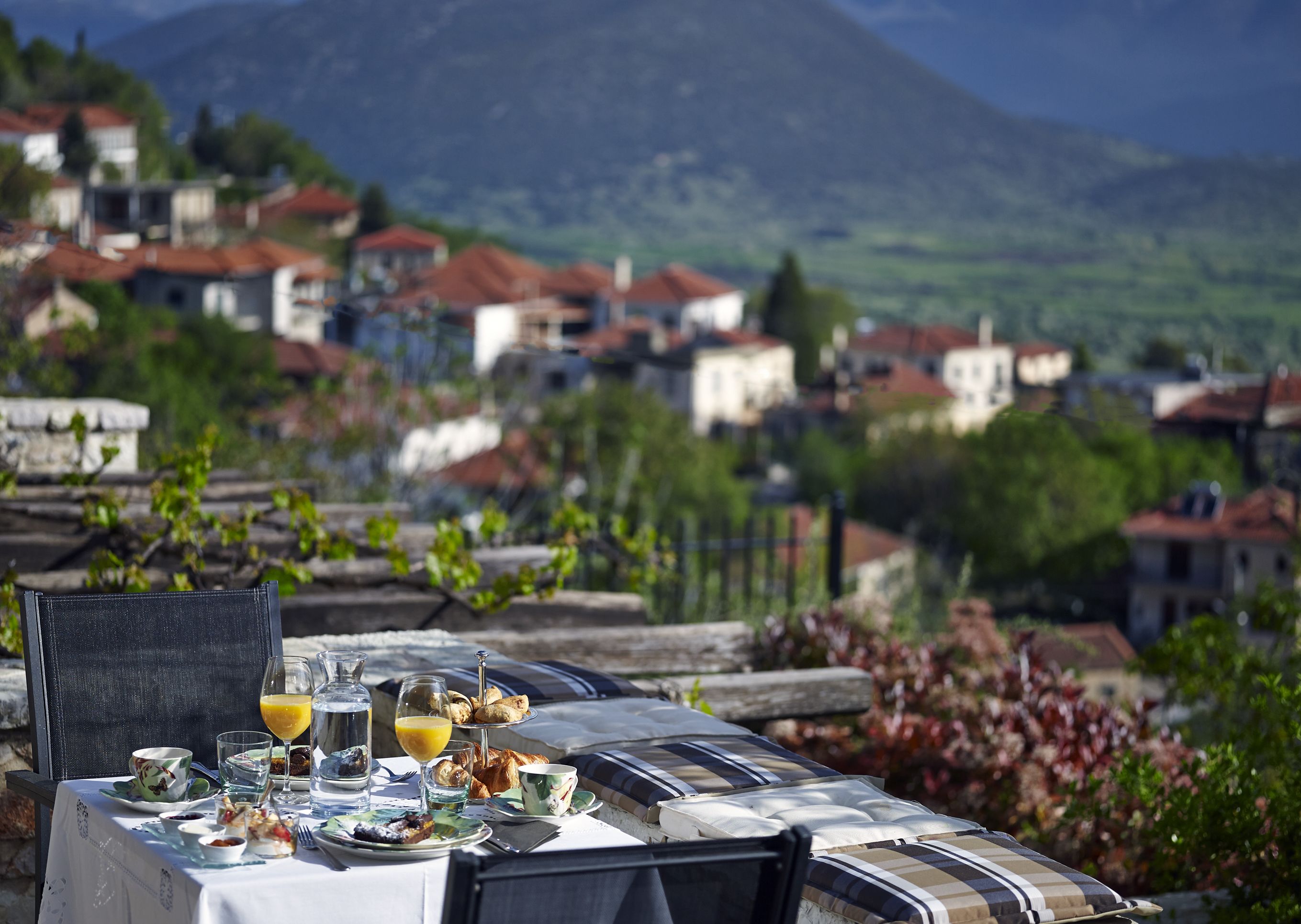 Une table dressée avec des aliments pour le petit-déjeuner, offrant une vue pittoresque sur un village et des montagnes.