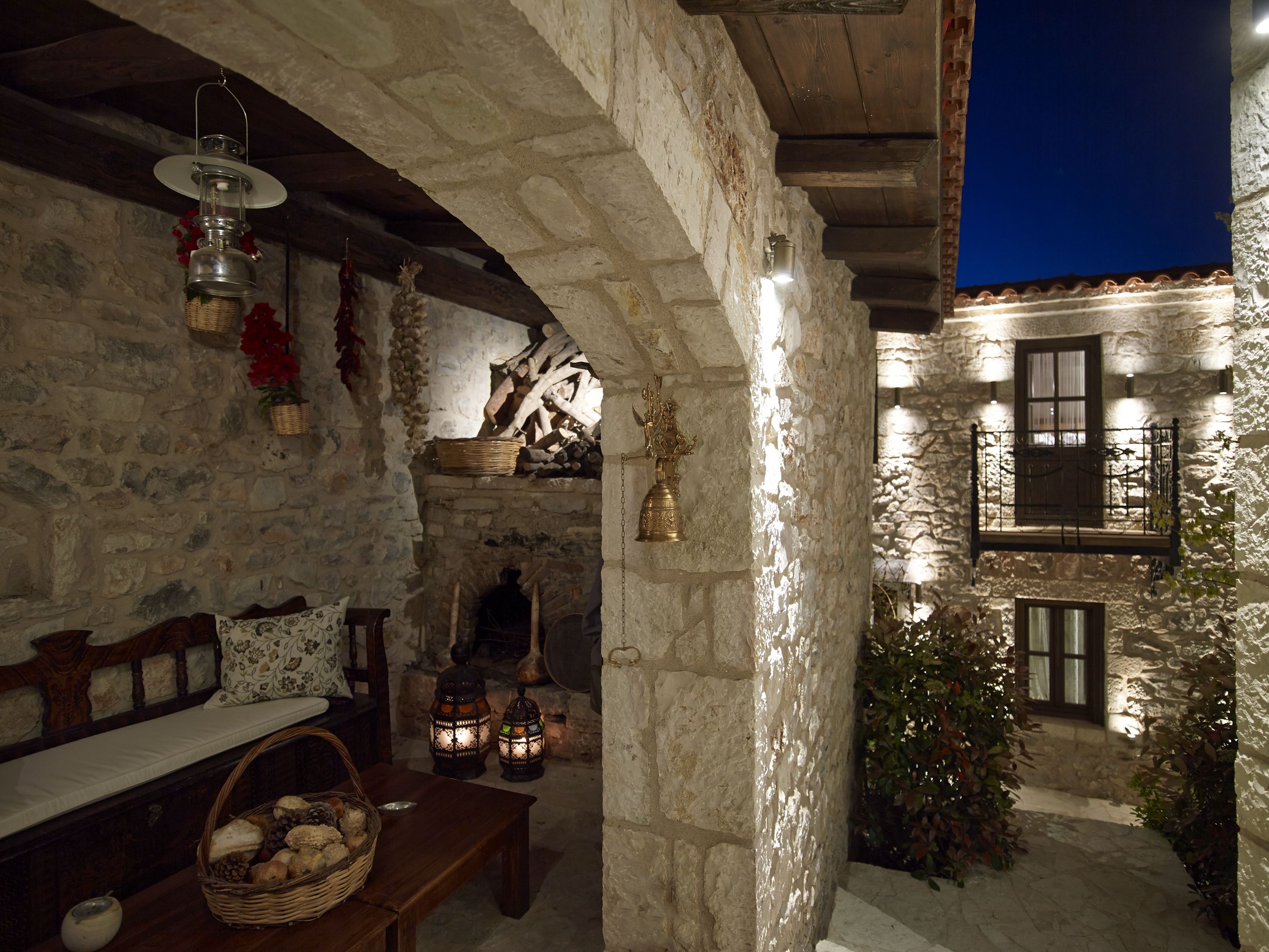 A stone-walled interior with a wooden bench, lanterns, and a basket of bread.