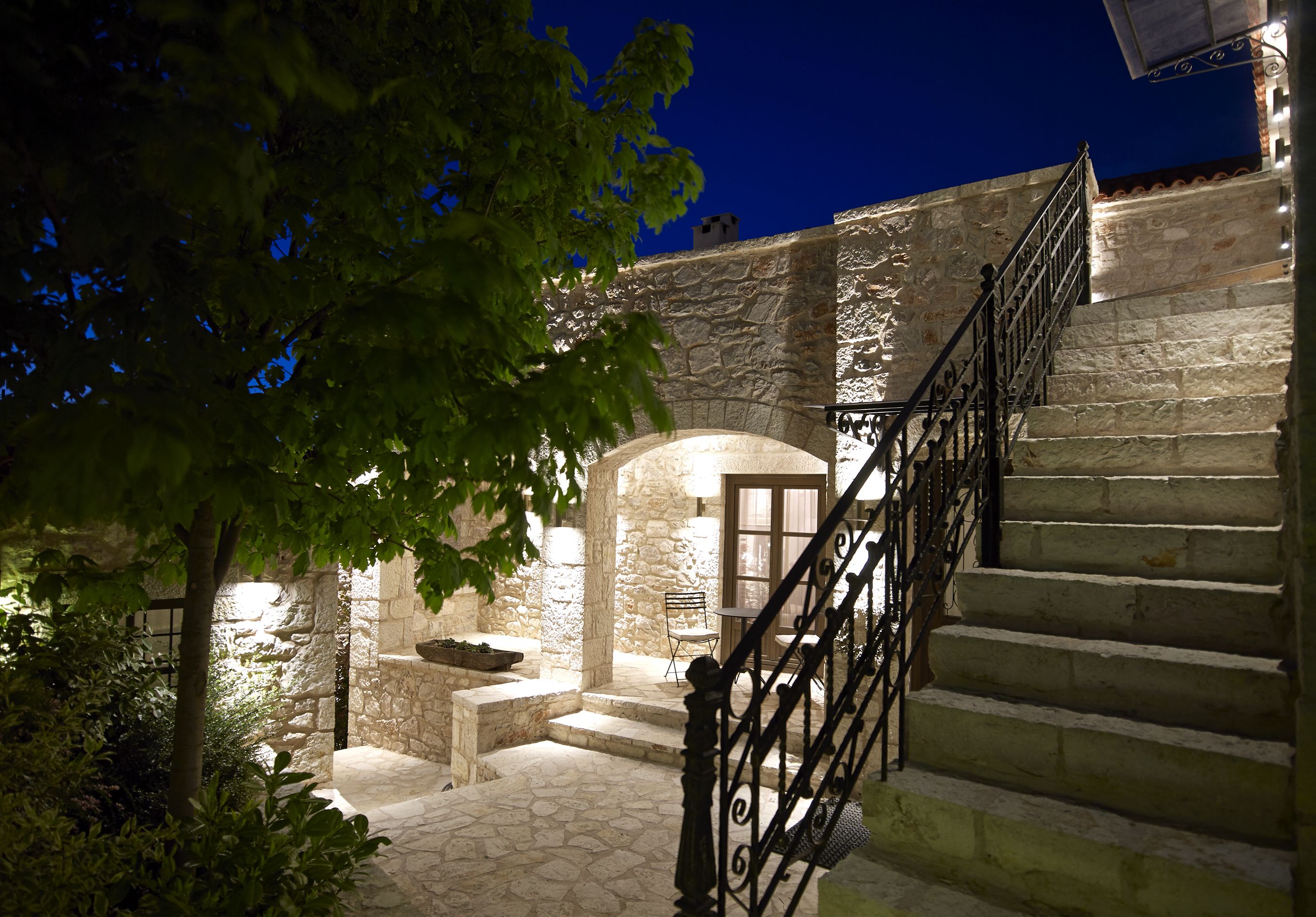 A stone staircase leading to a door, surrounded by greenery and stone walls.
