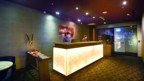 A hotel reception area with a reception desk, a seating area with a table and chairs, and a large window with a view of the cityscape. - Taipei 101 SPARKLE Hotel (Taipei)