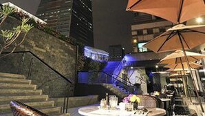 An outdoor dining area with tables and chairs, a staircase, and a tall building in the background. - Taipei 101 SPARKLE Hotel (Taipei)