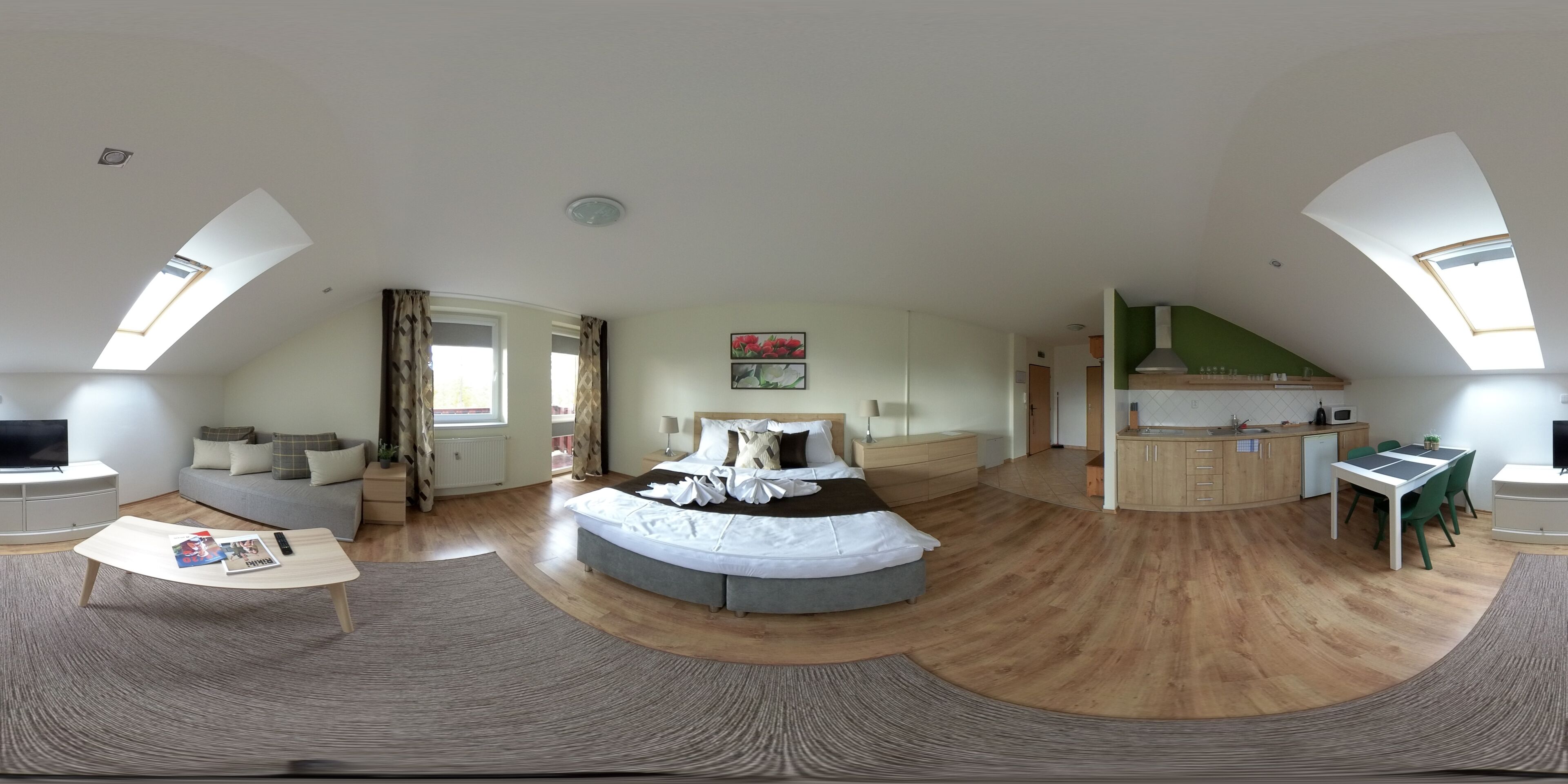 Una habitación amplia con una cama grande, un sofá, una mesa de comedor y una zona de cocina.