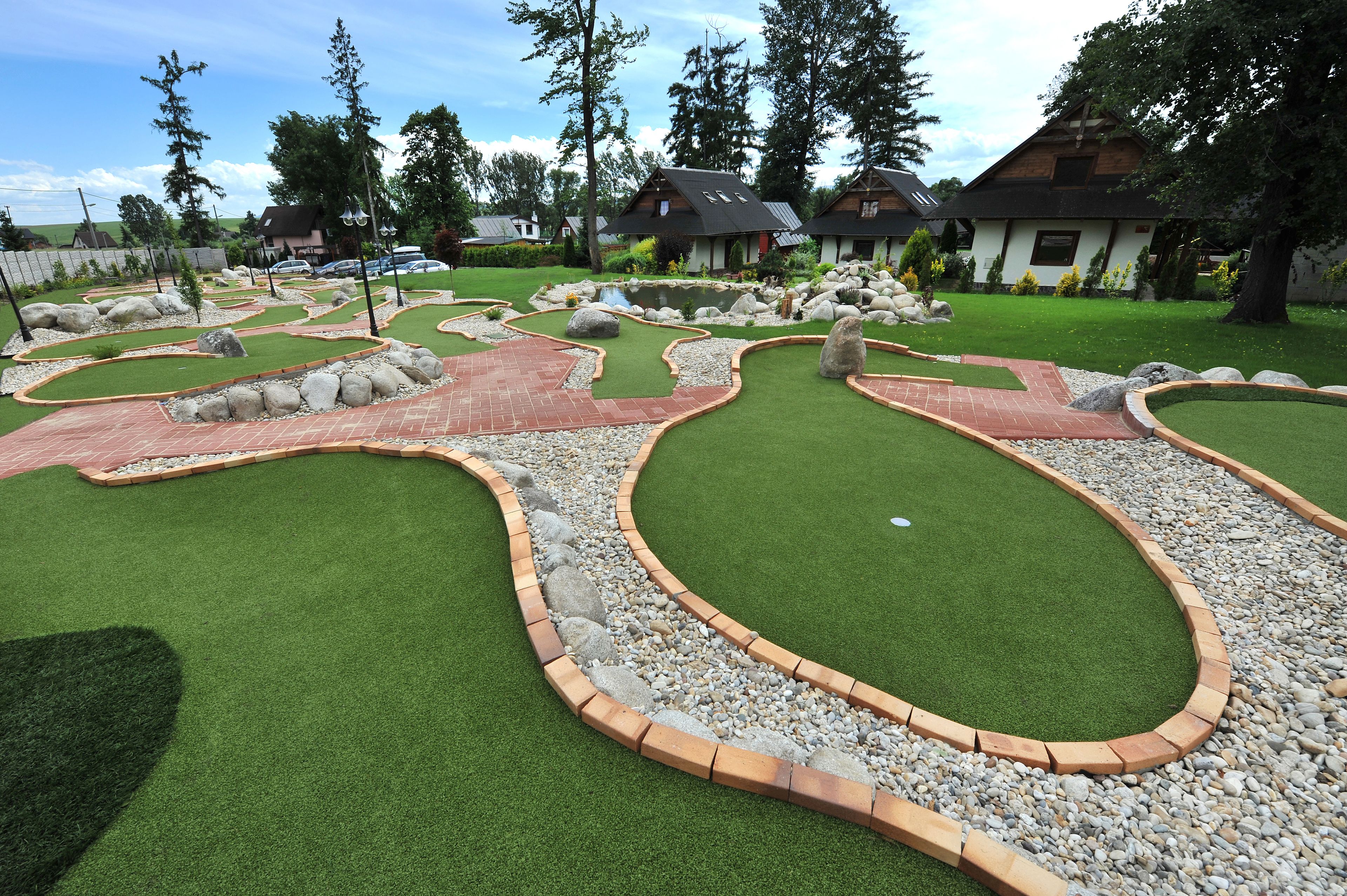 A landscaped garden with artificial grass, stone borders, and a pond.
