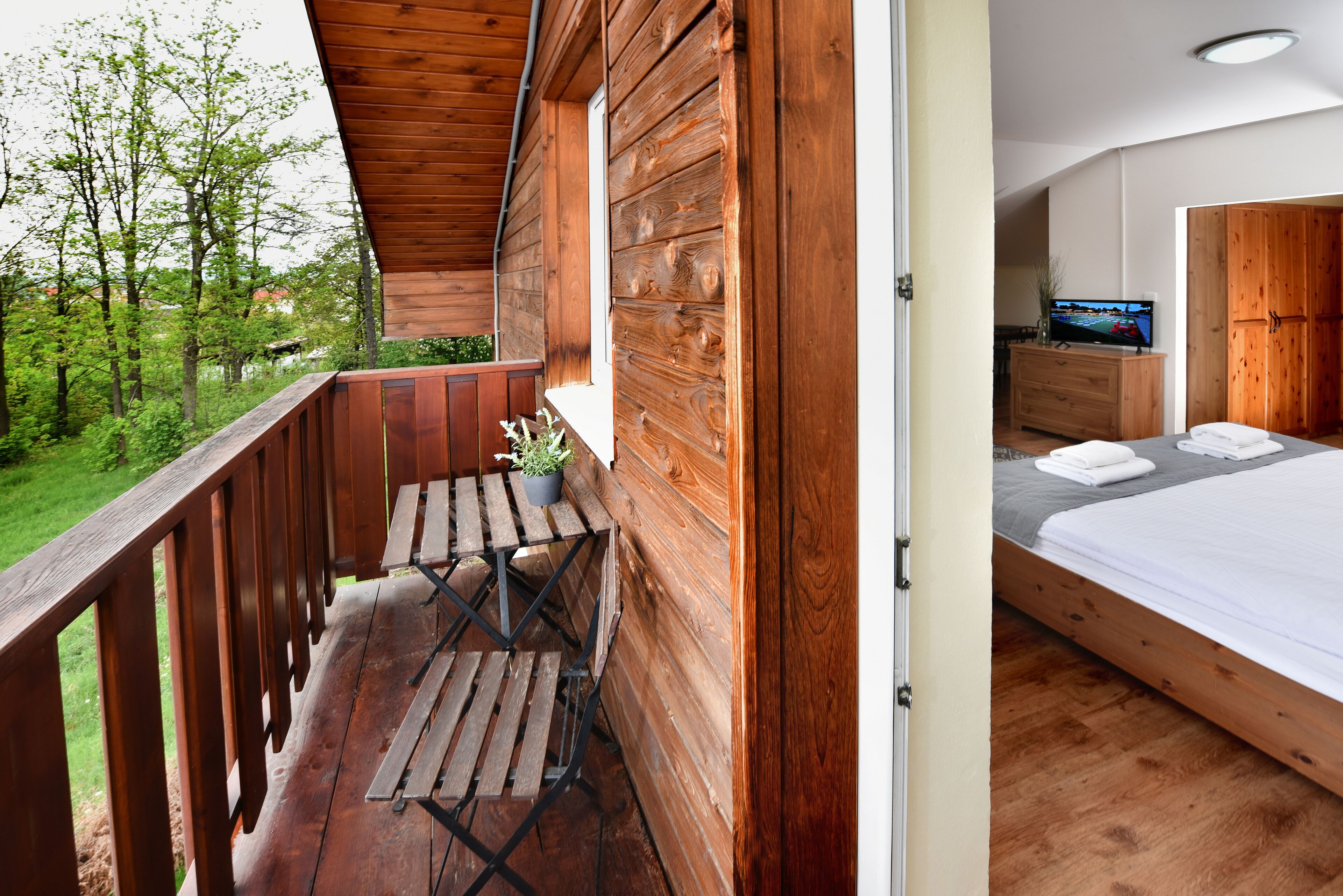 Eine Holz-Blockhütte mit Balkon, einem Bett und einem Fernseher im Schlafzimmer.