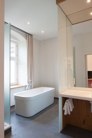 Een moderne badkamer met een vrijstaand bad, een douchecabine van glas en een wastafel met spiegel.