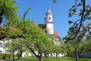 A building with a prominent tower and a red roof, surrounded by trees and greenery.