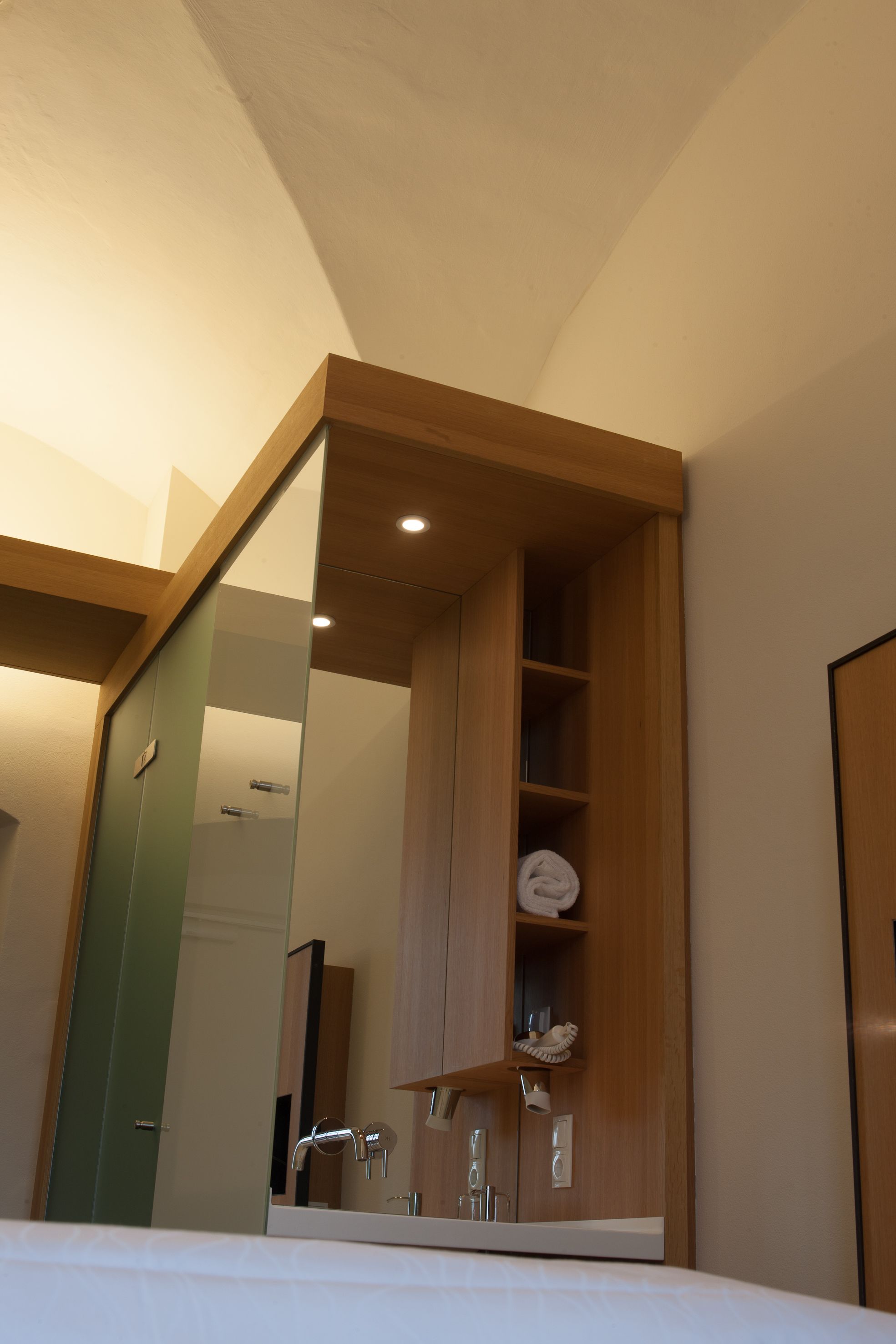 A modern bathroom with a wooden vanity, a mirror, and a sink.