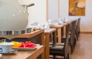 Een eethoek met een lange tafel, stoelen en een theepot.