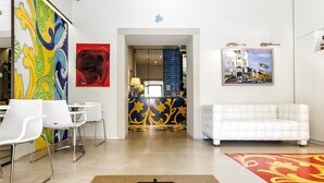 A modern hotel lobby with a reception desk, white sofas, and a colorful abstract painting on the wall. - Porta del Tocco Design Rooms (Taormina)