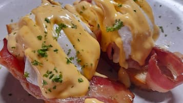 A plate of eggs benedict with ham and hollandaise sauce.